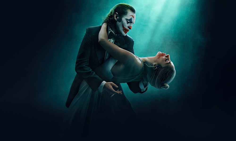 Cartaz do filme Joker: Folie à Deux, lançado em outubro de 2024, com Joaquin Phoenix e Lady Gaga. A imagem mostra os dois personagens em uma dança sob uma luz suave, com um fundo escuro e misterioso.