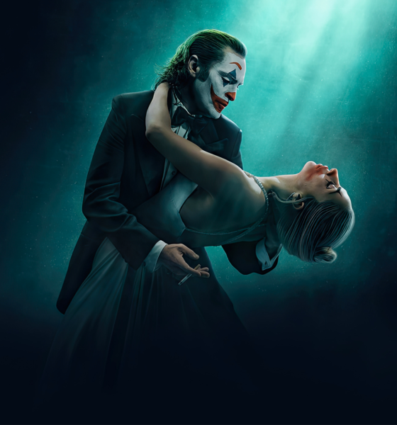 Cartaz do filme Joker: Folie à Deux, lançado em outubro de 2024, com Joaquin Phoenix e Lady Gaga. A imagem mostra os dois personagens em uma dança sob uma luz suave, com um fundo escuro e misterioso.